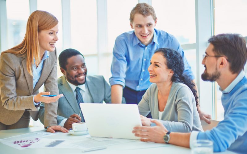 Group of business partners looking at smiling female explaining her ideas at meeting